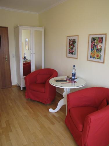a living room with two red chairs and a table at Strandhotel-Najade in Borkum