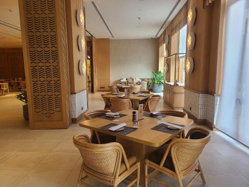 a restaurant with wooden tables and chairs in a room at Novotel Hyderabad Airport in Hyderabad