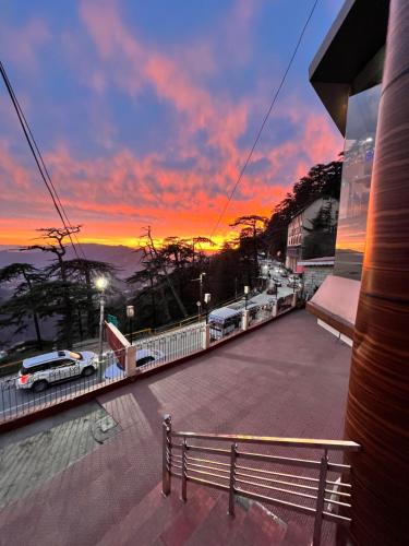 a view of a sunset from a building with a bench at Hotel Victory in Shimla