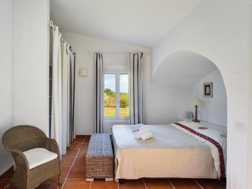 a bedroom with a large white bed and a chair at Case Li Conchi G in Castiadas