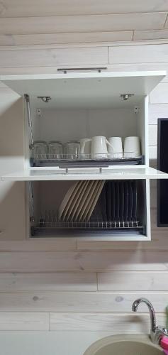 a shelf with cups and utensils in a kitchen at Відпочинково-ресторанний комплекс "Затишна садиба" in Luchin