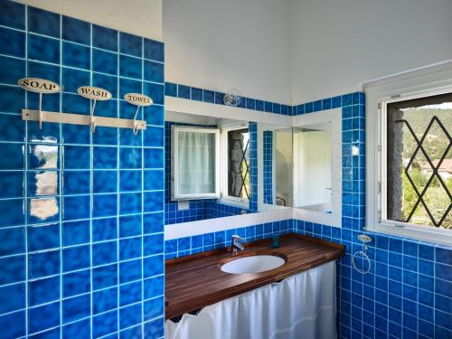 Baño de azulejos azules con lavabo y espejo en Case Li Conchi G, en Castiadas