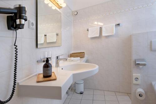 a white bathroom with a sink and a shower at Hotel Rotkreuzplatz in Munich