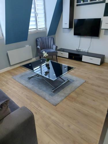 a living room with a glass coffee table and a television at WIFI- STADE DE FRANCE- BASILIQUE CATHEDRALE MONSEJOURASAINTDENIS in Saint-Denis