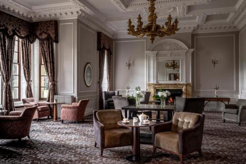 a living room with chairs and a table and a chandelier at Crathorne Hall in Yarm