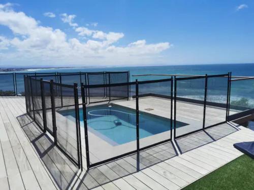 a swimming pool on a deck with the ocean in the background at Luxury Beach House in St Francis Bay