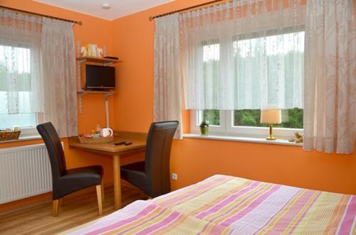 sypialnia z pomarańczowymi ścianami, biurkiem i łóżkiem w obiekcie B&B Brandholz w mieście Goldkronach