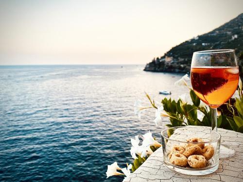 a glass of wine sitting on a table next to the water at Idillioravello in Ravello