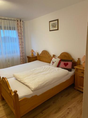 a bedroom with a wooden bed with white sheets at Das kleine Landhotel in Dorsten