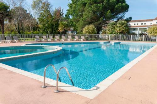 a large swimming pool with blue water and chairs at Village Pierre & Vacances Moliets in Moliets-et-Maa