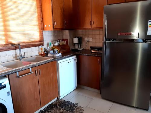 a kitchen with a stainless steel refrigerator and wooden cabinets at Nayia Paradise Villa! Best Villa in Cyprus in Paphos City