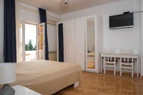 a bedroom with a bed and a table and a television at Boutique B&B Villa Carmen in Mlini