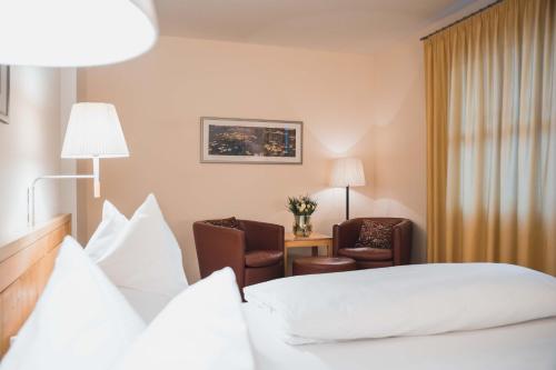 a hotel room with a bed and two chairs at Felbermayer Hotel & AlpineSpa-Montafon in Gaschurn