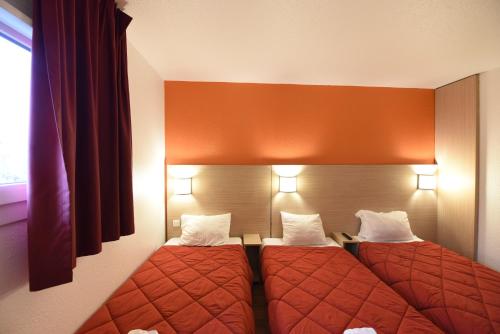two beds in a hotel room with red sheets at Première Classe Rosny Sous Bois in Rosny-sous-Bois