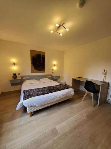 a bedroom with a large bed and a desk with a chair at Les Cèdres Bleus in Aurec-sur-Loire