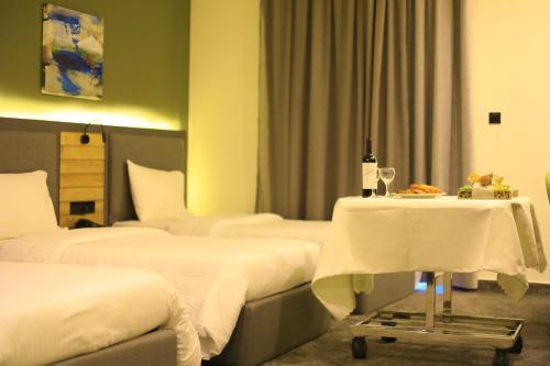 a hotel room with three beds and a table with a bottle of wine at Aitch Boutique Hotel - an LIH Hotel in Madaba