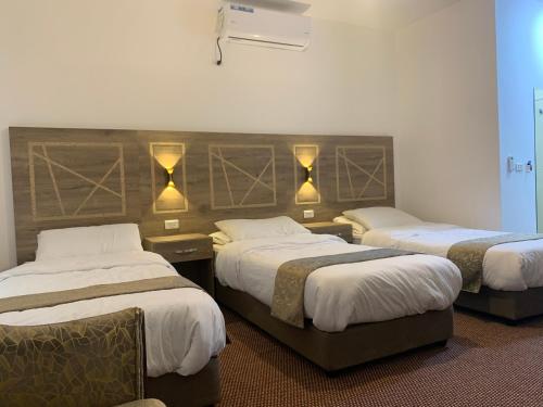 um quarto de hotel com duas camas e luzes na parede em Asad Apt. em Wadi Musa