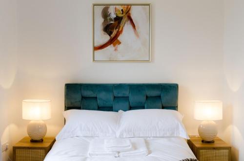 a bedroom with a bed with a blue headboard and two lamps at Central Chic Margate Apartment, edge of Old Town! in Kent
