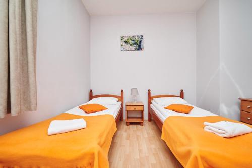 two beds in a room with orange sheets at Hotelik Gołdap in Gołdap
