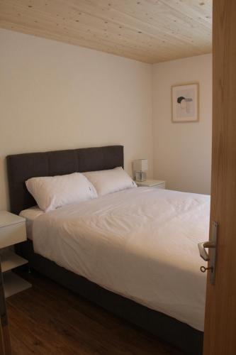 a bedroom with a large bed with white sheets at Mountain Oasis Apartment Kandersteg-Adelboden in Kandergrund