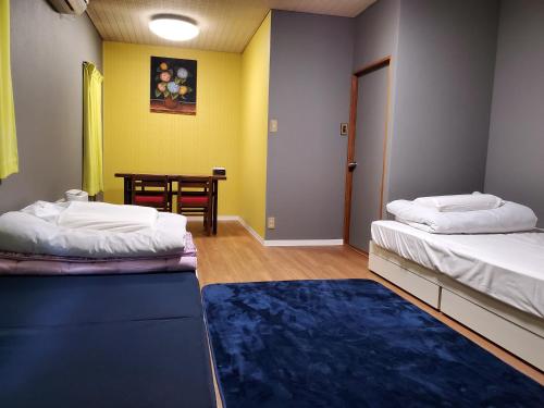 a room with two beds and a table in it at Naoshima Kowloon in Naoshima