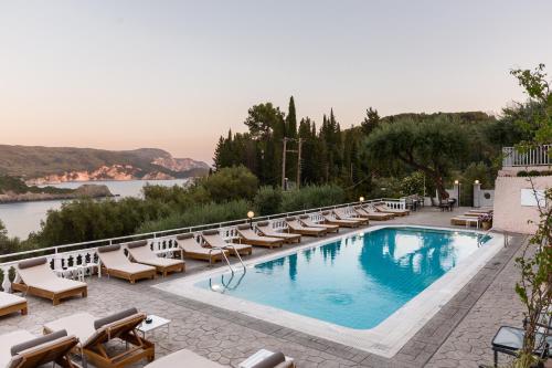 a swimming pool with lounge chairs and a view of the water at Odysseus Hotel in Paleokastritsa