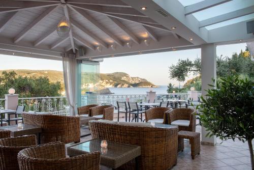 a restaurant with tables and chairs and a view of the ocean at Odysseus Hotel in Paleokastritsa