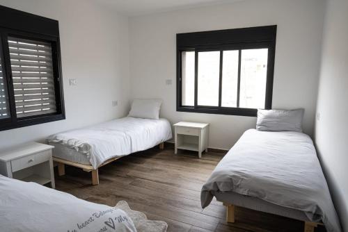 Zimmer mit 2 Betten und 2 Fenstern in der Unterkunft סוויטות ביתרא החרמון in Mas'ada