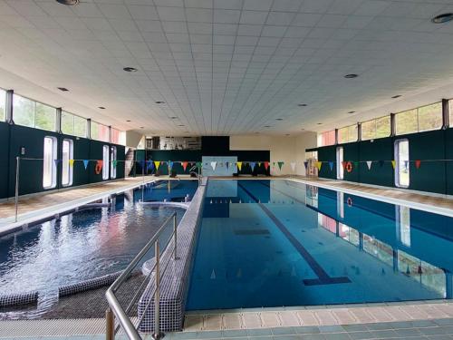 a large swimming pool with blue water in a building at Estación de Montaña Manzaneda in Puebla de Trives