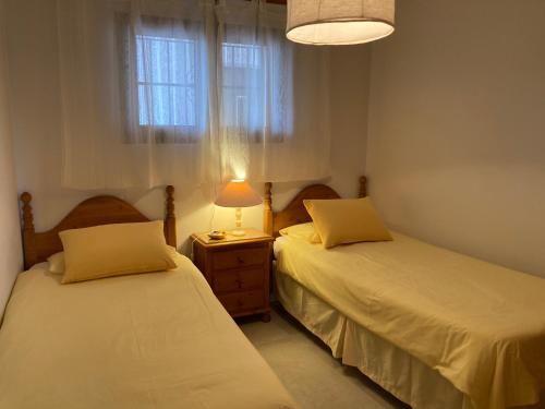 a bedroom with two beds and a lamp and a window at Apartamento Agua Azul in Jávea