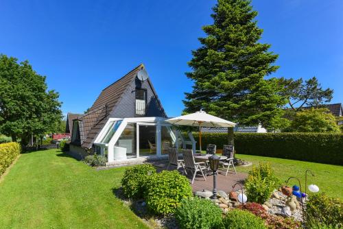 une maison avec un parasol, une table et des chaises dans l'établissement Ferienhaus Boje 13, à Neuharlingersiel