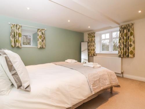 a bedroom with a large white bed and two windows at Paradise Cottage in Harrogate