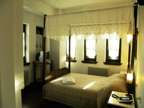 a bedroom with a bed and two windows at Hotel Petrino in Makrinitsa