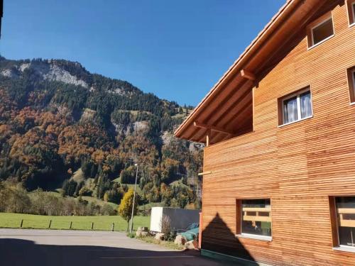 a wooden building with a mountain in the background at Mountain Oasis Apartment Kandersteg-Adelboden in Kandergrund