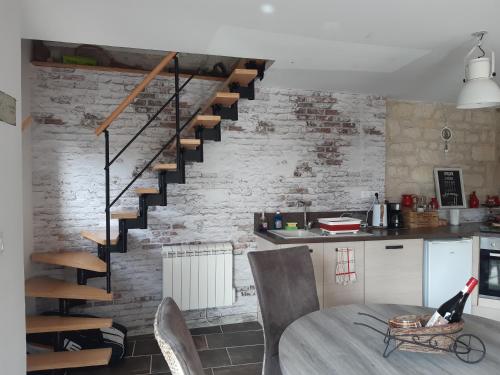 a kitchen with a brick wall with a spiral staircase at Oclos du RhuisO in Rhuis