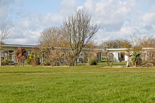 a house with a green lawn in front of it at Pakefield Holiday Village - Adults Only in Lowestoft