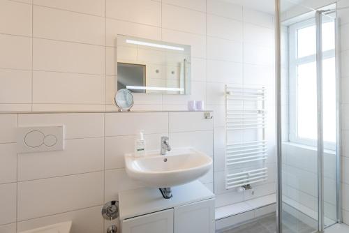 een witte badkamer met een wastafel en een spiegel bij Sölring Hüs, App 4 in Wenningstedt