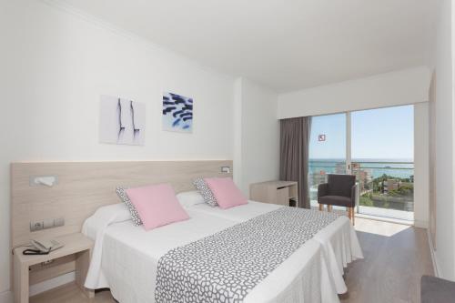 um quarto com uma cama com almofadas cor-de-rosa e uma janela em Hotel Timor em Playa de Palma