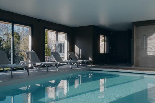 a room with a pool with chairs and windows at La Fraîchette-Hôtel & Spa in Honfleur