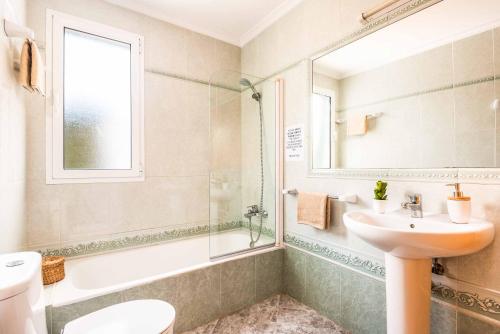 Un baño con lavabo, inodoro y espejo. en Villa Karoline, en Cala en Forcat