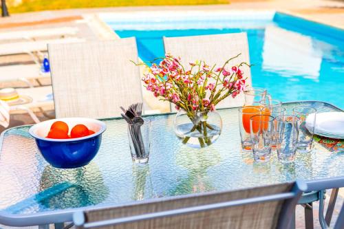 a glass table with a bowl of fruit and a bowl of flowers at Villa Wisteria in Lachi