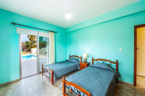 two beds in a blue room with a pool at Villa Wisteria in Lachi