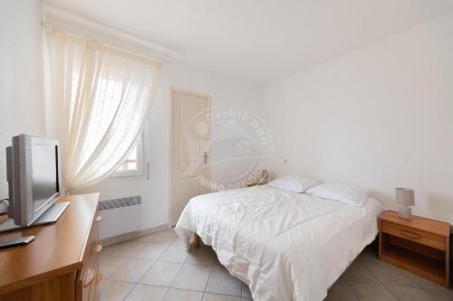 Schlafzimmer mit einem Bett, einem Schreibtisch und einem TV in der Unterkunft AS14627 - P3 au coeur du Centre Ville avec parking privé in Le Grau-du-Roi