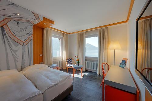 アスコナにあるAlbergo Carcani by Ketty & Tommyのベッド、デスク、窓が備わるホテルルームです。