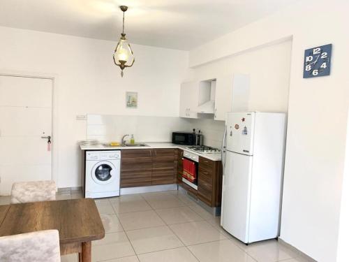 cocina con nevera blanca y mesa en Beautiful & Quiet Two-Bedroom Apartment with Private Garden Lukomorye C1, en Kyrenia