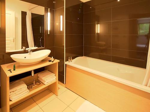 a bathroom with a sink and a bath tub at Duplex avec piscine et sauna in Jausiers