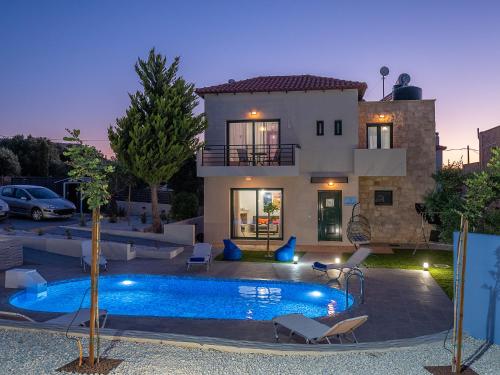 a villa with a swimming pool in front of a house at Anna Luxury Sea View Private Villa in Gouves