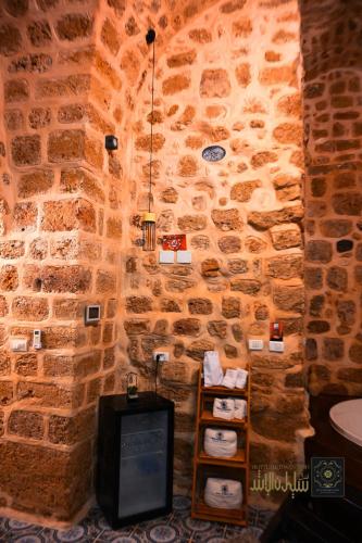 a room with a stone wall with a tv in it at Suleiman Pash in ‘Akko
