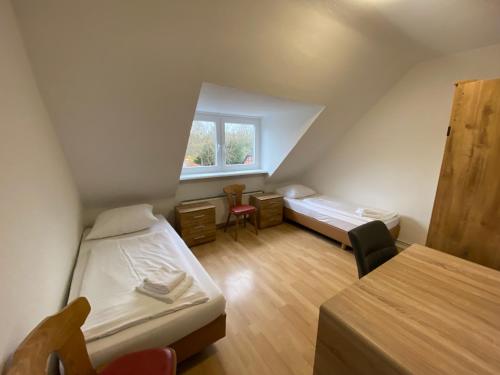 een zolderkamer met 2 bedden en een raam bij Othman Appartements Groß Buchholzer Straße 16a in Hannover