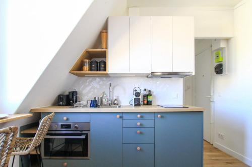 - une cuisine bleue avec des placards blancs et un évier dans l'établissement Charming 2-Room 21m Comfort Sacré-Cœur View, à Paris